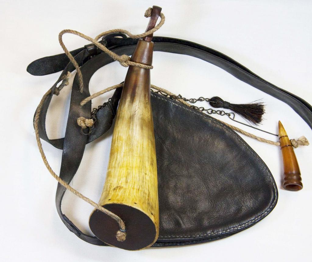 Horn #3 - Bag #8 - A plain southern powder horn attached by linen cord to a Southern heart shaped shot pouch laying on a flat surface.